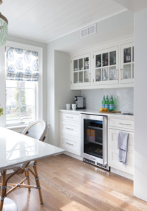 All white kitchen with stainless steel wine fridge and wood floors