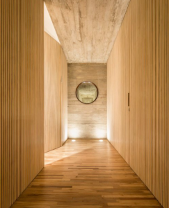 Hallway with wood floor, wooden walls and a round mirror at the end