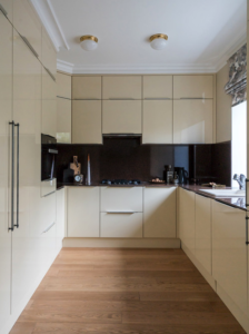 Light cream shiny cabinets with a dark backsplash and wood floors