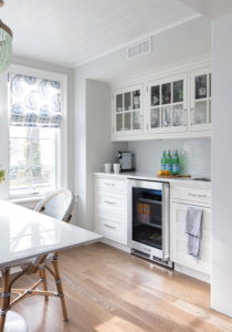 White kitchen with glass upper cabinet doors, white walls and white rectangular dining table
