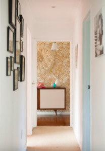 Credenza with white doors against tan wallpaper at the end of a hallway