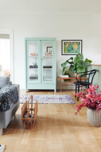 Pale green china cabinet on light wood floors with eclectic furniture