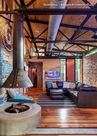 Industrial looking living room with leather sectional on right and large floor fireplace