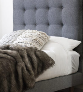 blue tufted bed frame and faux fur throw