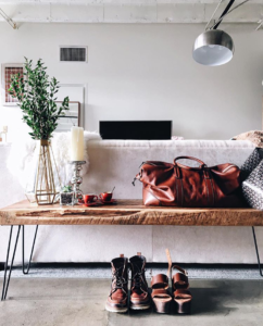 White sofa facing away with wood bench against the back