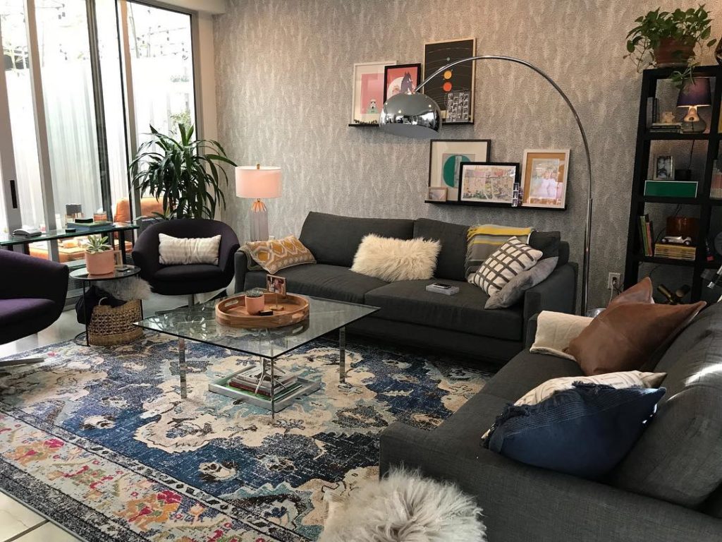 black sofa middle with black chair on right around square glass coffee table