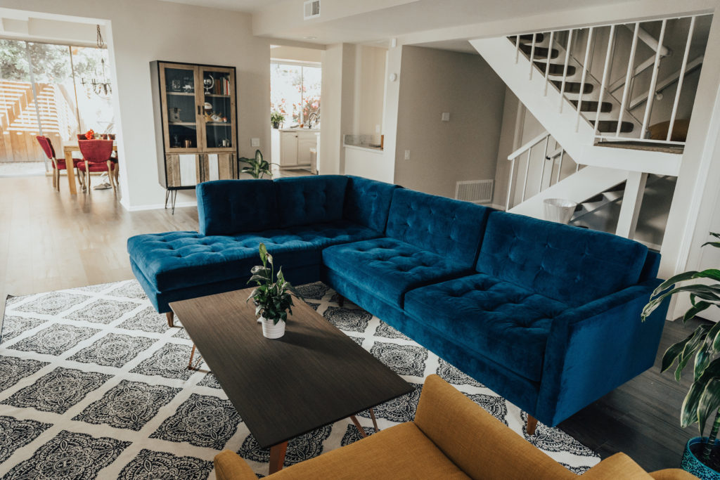 blue sofa in room with yellow chair and wooden coffee table placed on a black and white rug