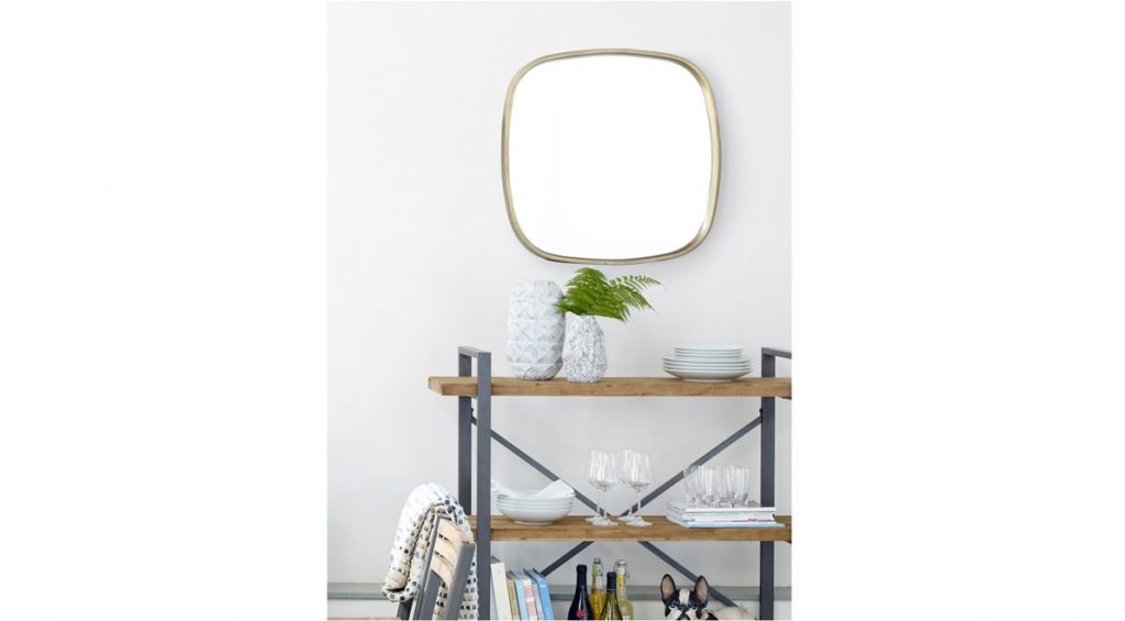 wooden and black bar cart with vases, bowls, glasses on it with a mirror behind it