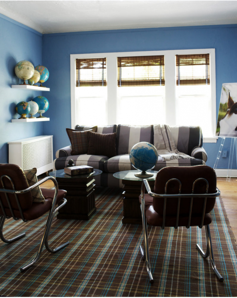 purple striped sofa, two red and metal chairs, two coffee tables, multiple globes, painting, striped rug and large window