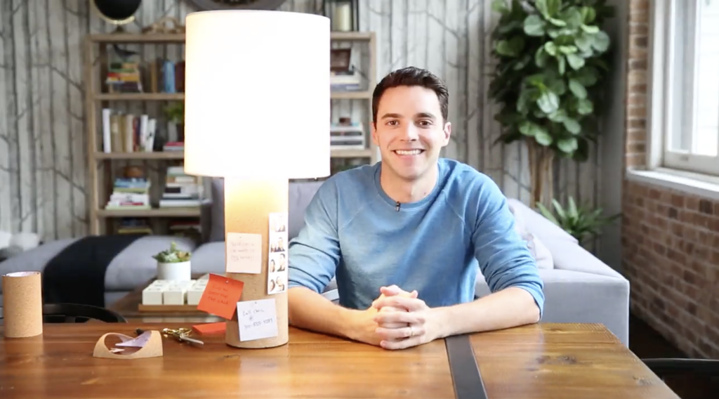 Man seated at a table in a blue shirt with a bright table lamp