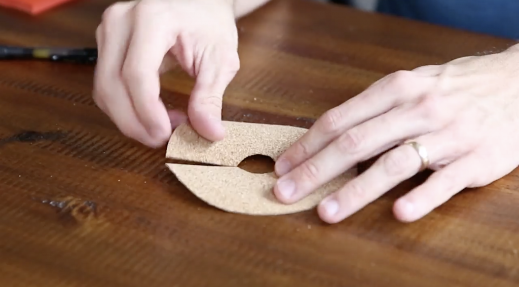 Hands showing a piece of cork paper cutout with a hole in the center
