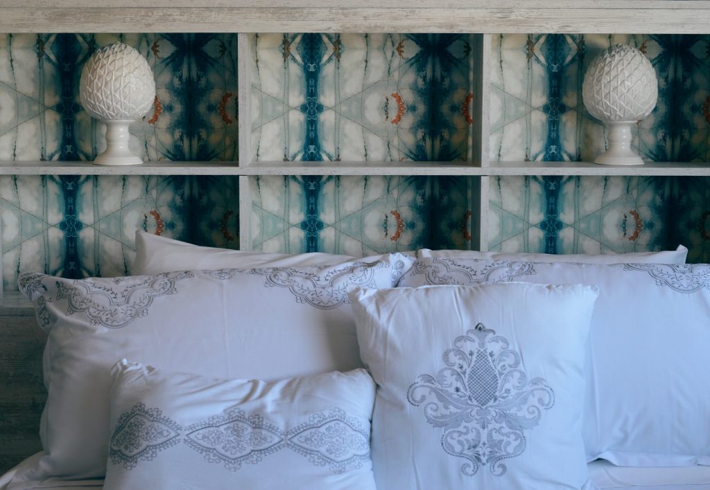 Detail view of intricate white pillow covers on a bed with a blue and white storage headboard