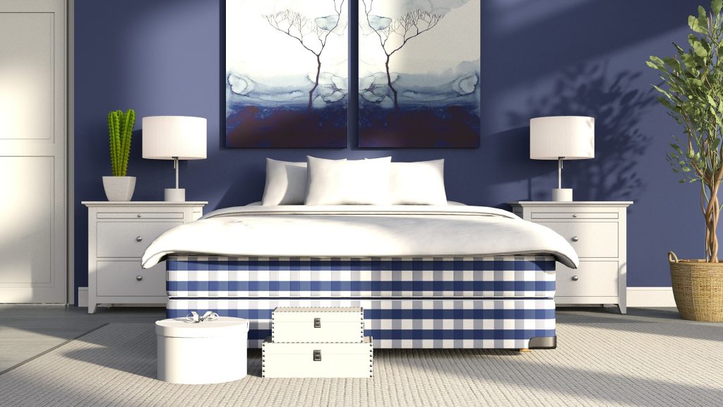 Blue and white checkered bed with white bedding and white nightstands against a blue wall