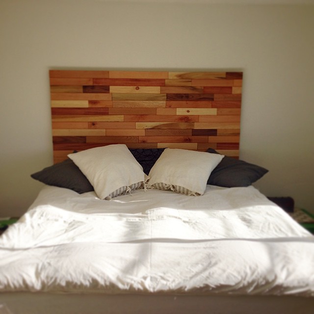 Bed with a wooden headboard and white and black pillows against a beige wall