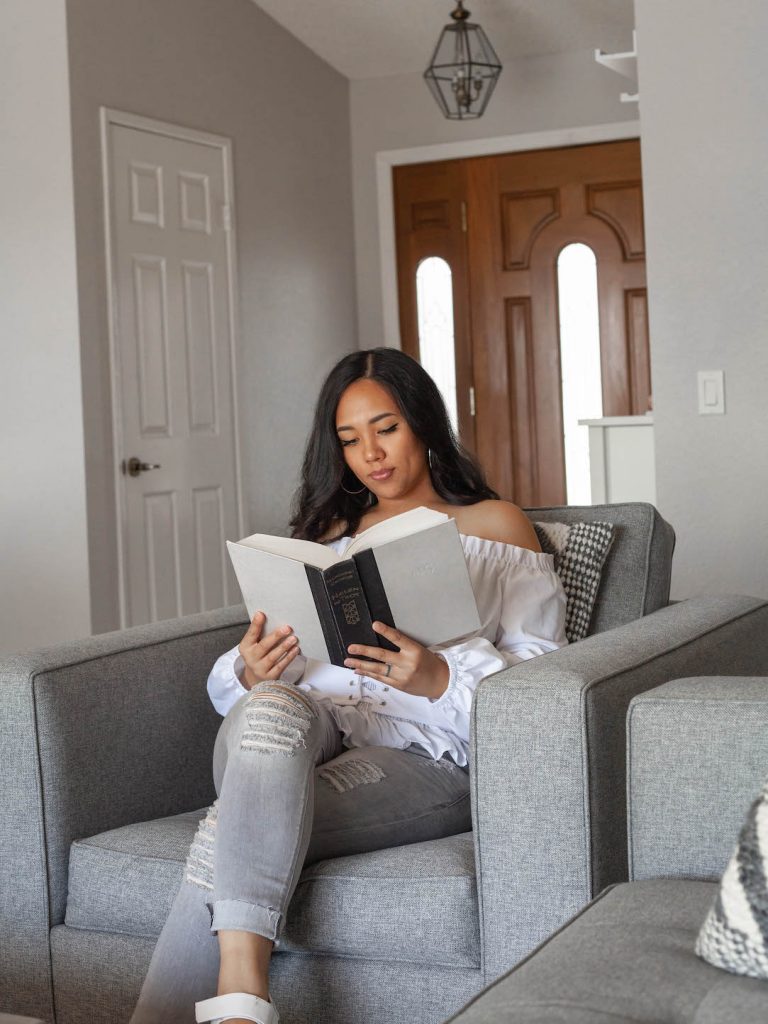 woman in grey chair reading a book