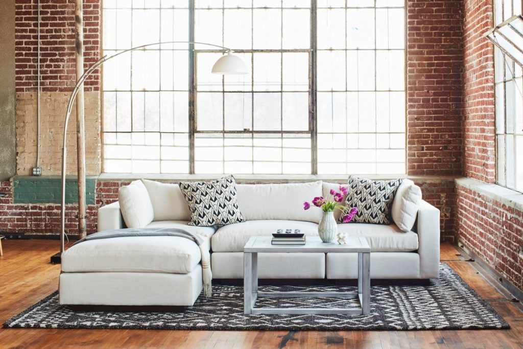 white sofa with pillows on a white and black rug with coffee table