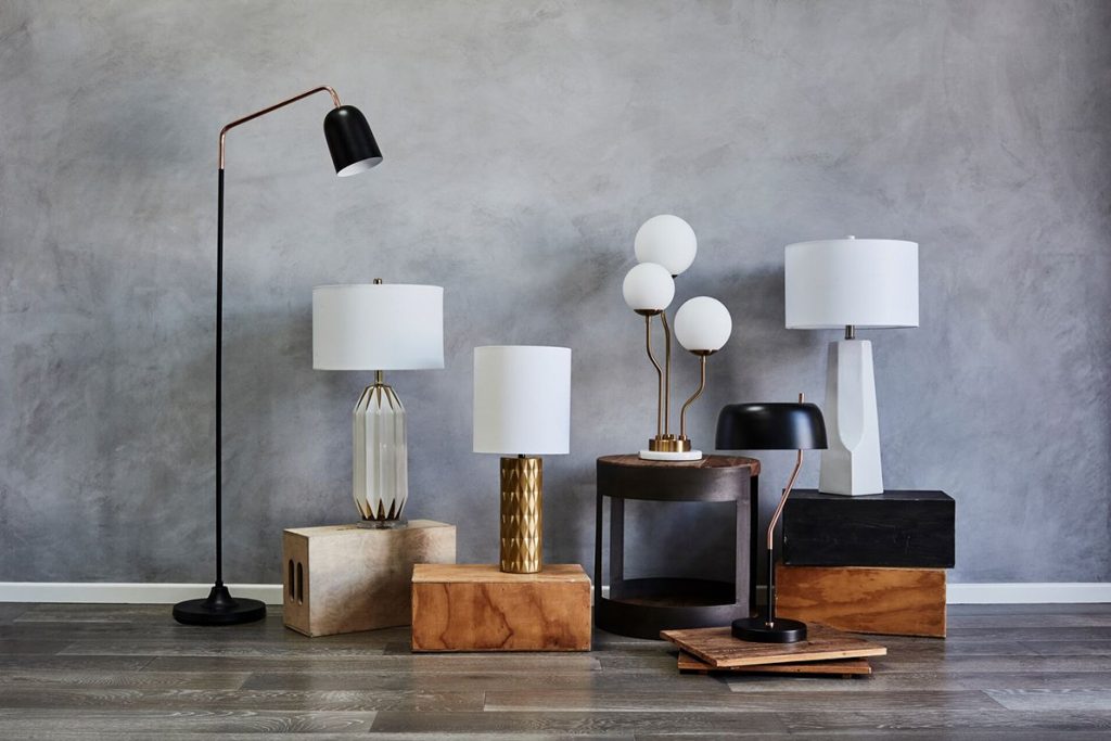 variety of table and floor lamps on a wood floor against a grey wall