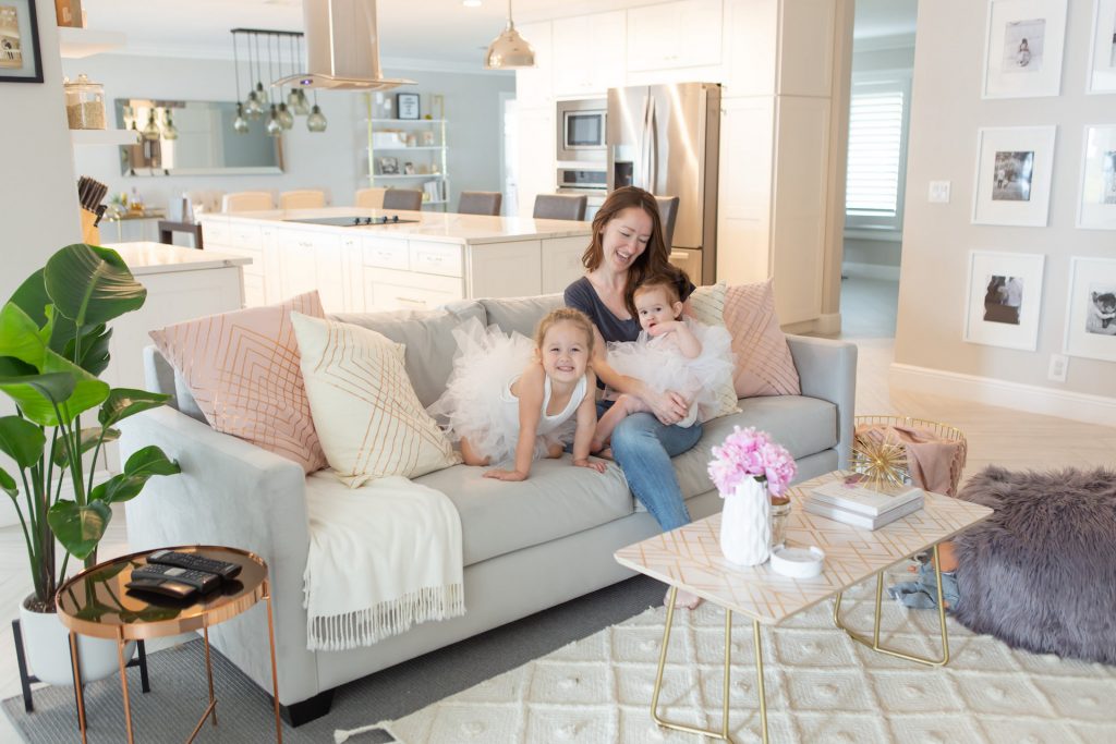 woman and two young girls sitting on grey sofa with pillows