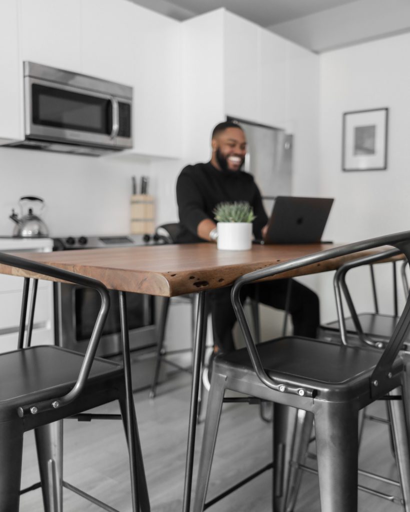 man smiling at wooden table with a laptop