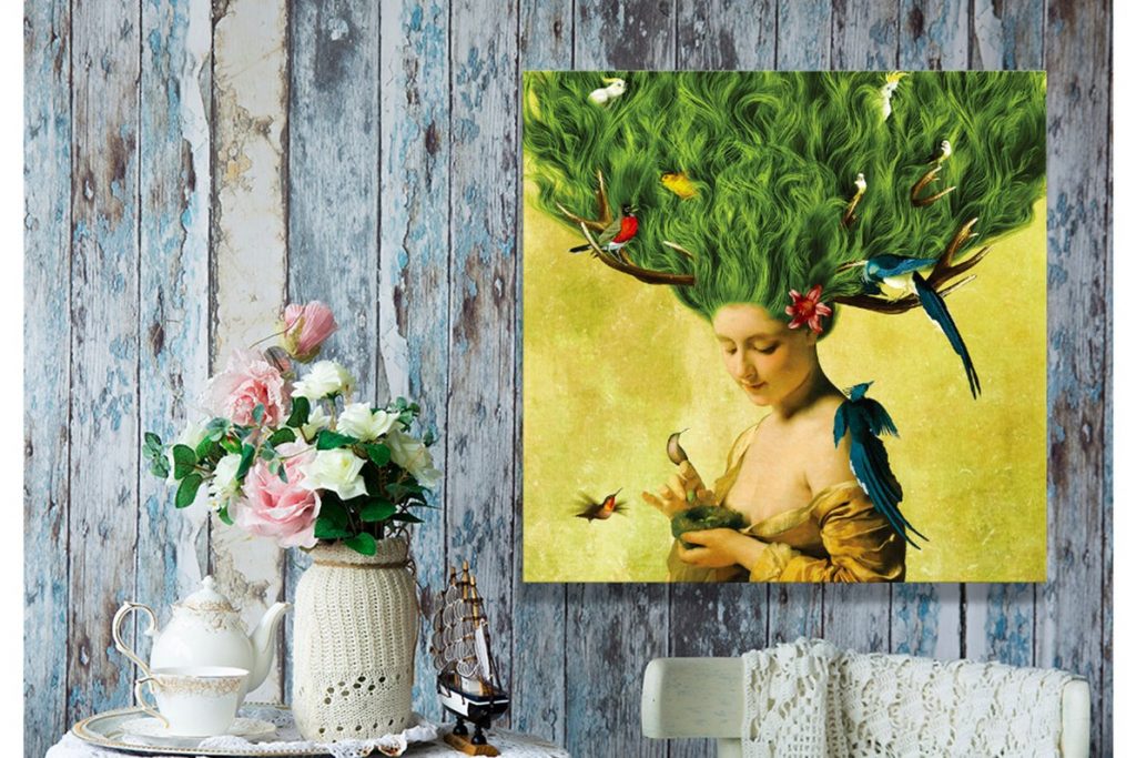 yellow and green painting with a woman and birds on it beside flowers, teacups and a white chair