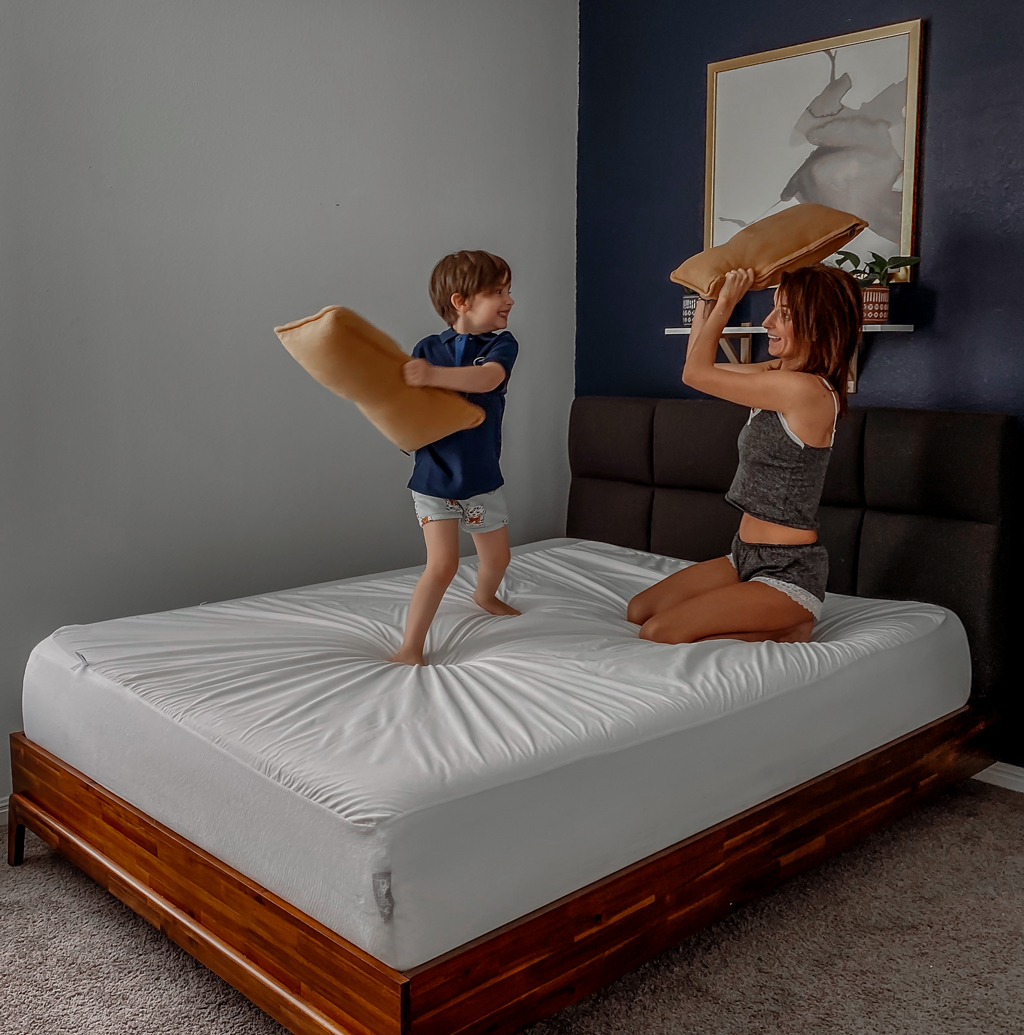 a mom and son having a pillow fight on a bed