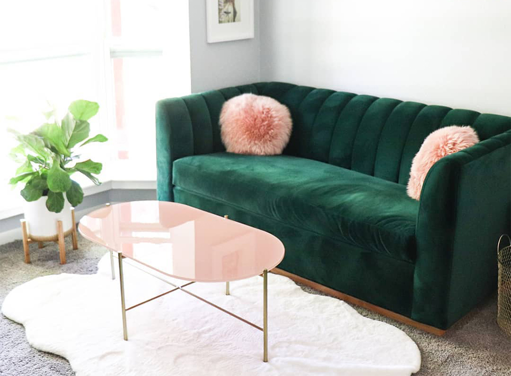 green sofa with pillows next to a coffee table and plant