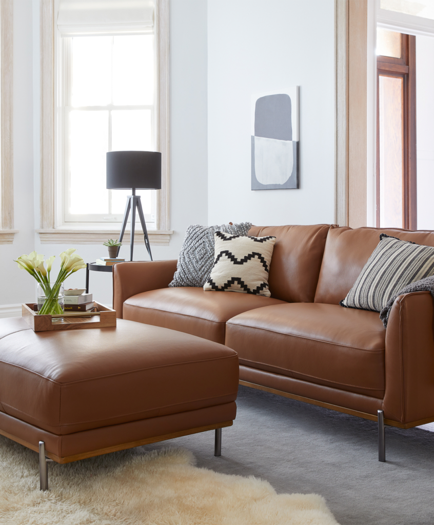 brown leather sofa with pillows on it