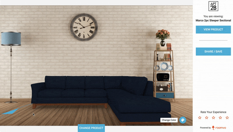 dark blue sofa, clock, lamp and book shelf with books and a flower on it