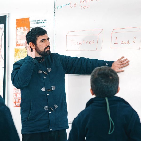 Profesor imparte su clase a los alumnos, este explica con ejemplos en el tablero