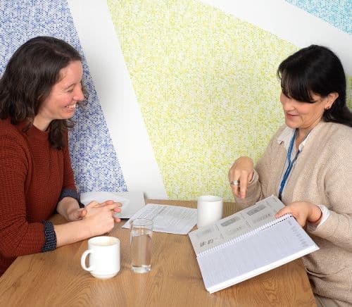 Mujeres reunidas en torno a un café, debate algunos apuntes de un cuaderno