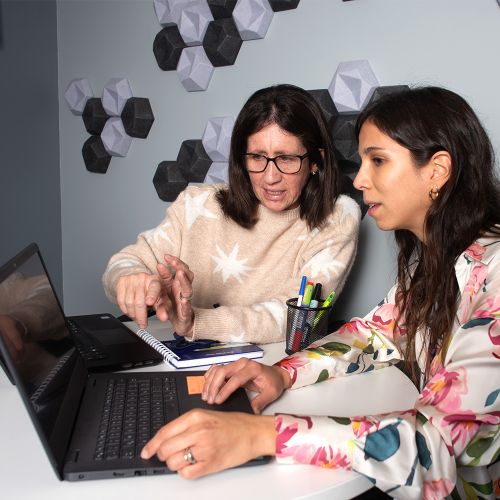 Dos mujer trabajan en equipo, mientras revisan algunas cosas en un computador