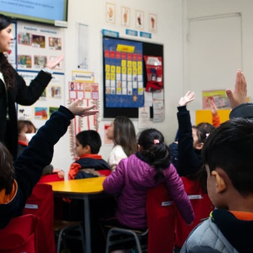 Niños en el salón de clases, participan activamente levantando la mano