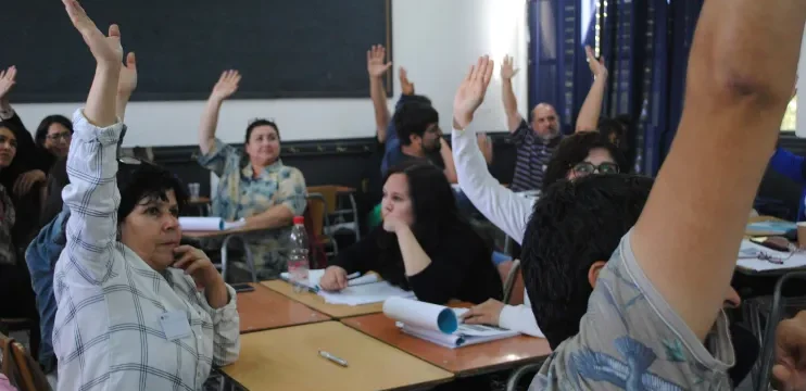 Docentes participativos en algún curso, estos están alzando la mano durante una pregunta