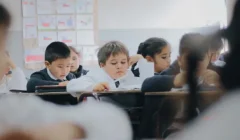 Varios alumnos reunidos en su salón de clase, mientras reciben su clase por parte de su profesor