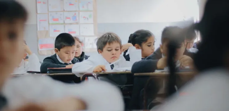 Varios alumnos reunidos en su salón de clase, mientras reciben su clase por parte de su profesor