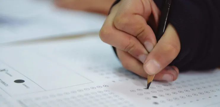 Mano de un alumno toma un lápiz para realizar alguna prueba