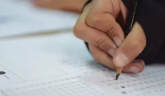 Mano de un alumno toma un lápiz para realizar alguna prueba de Aptus