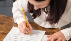 Maestra con lápiz en la mano, revisa alguna pruebas de sus estudiantes
