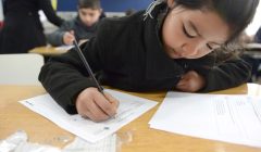 Niña escribiendo en un papel en el colegio