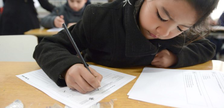 Niña escribiendo en un papel en el colegio