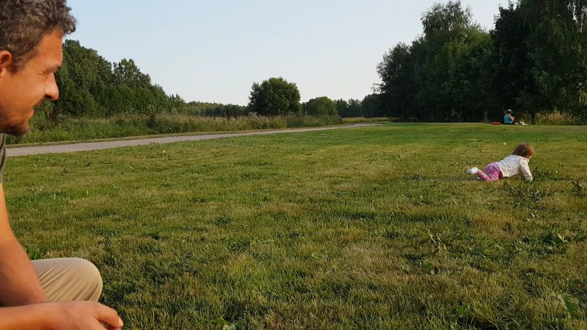 man watching child play in field