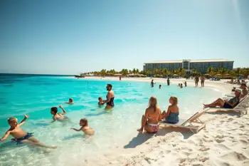 Families enjoying an all-inclusive resort beach in Cancun with children playing in turquoise waters, white sandy beach, palm trees, and multi-level resort buildings in background