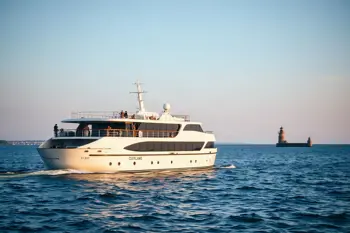 Small cruise ship sailing on Lake Erie near Cleveland with a lighthouse and city skyline