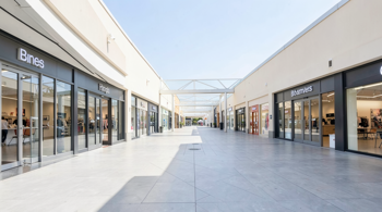 A modern open-air outlet shopping center showing various storefronts and clean walkways.