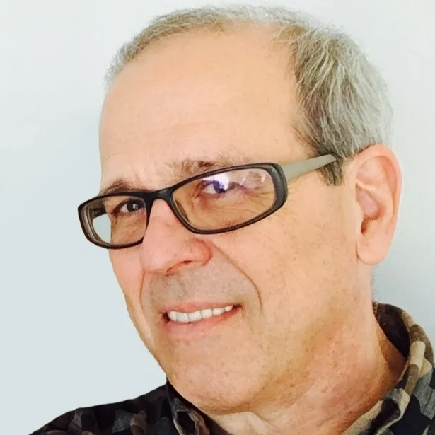 3/4 profile of white man with gray hair and glasses smiling