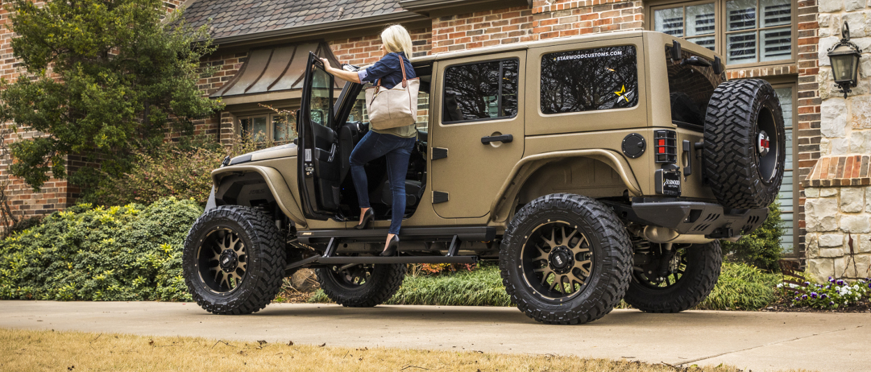 Woman climbing ARIES ActionTrac™ power steps into Jeep Wrangler JK