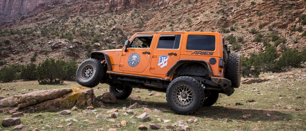 Orange 2013 Jeep Wrangler JK Unlimited rock crawler with ARIES Rocker Steps