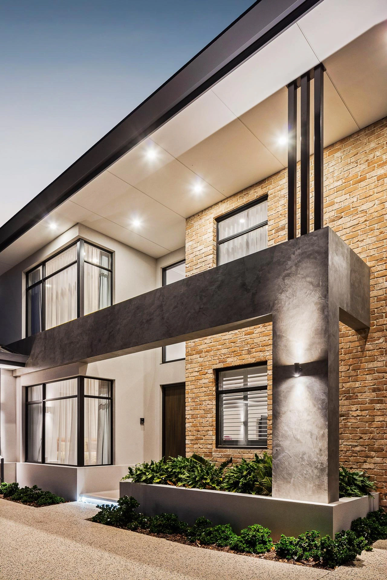 Modern residential building with brick and stucco facade and illuminated exterior lighting