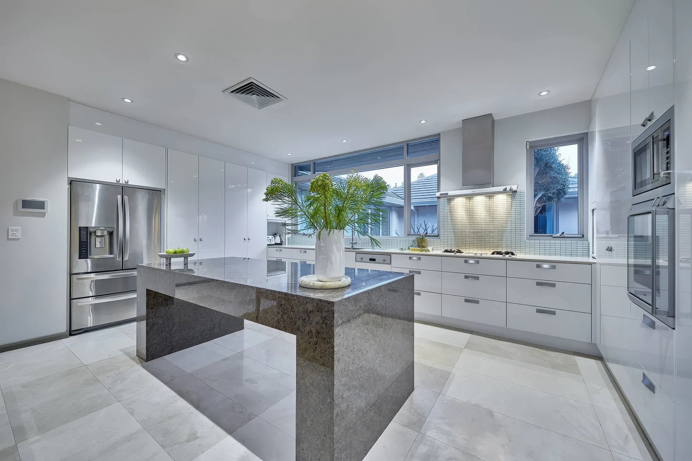 Modern white kitchen with central island and large windows