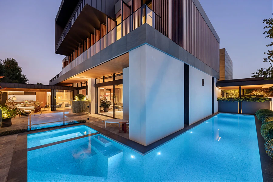 Luxury home exterior and illuminated swimming pool at dusk